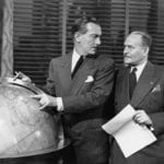 Two-men-discussing-location-on-world-map