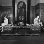 Man-and-woman-perched-at-either-end-of-long-desk